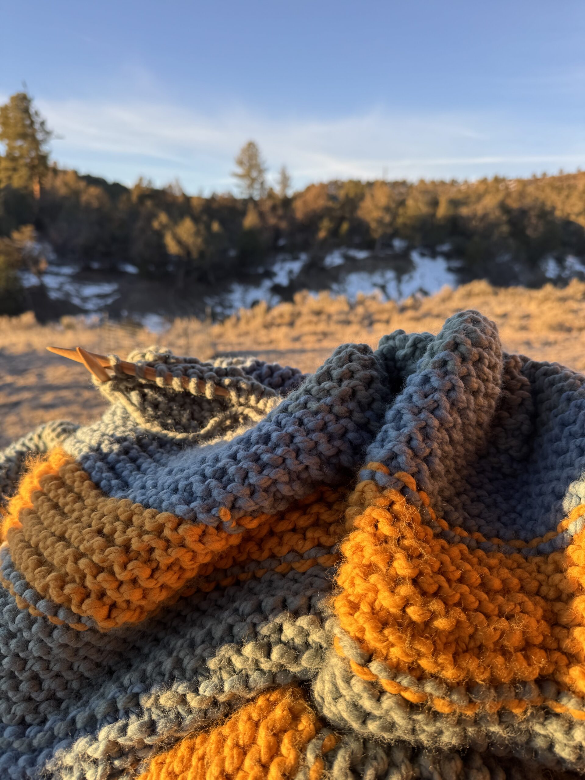 Knitting the Gratitude Blanket outside at golden hour in Colorado shows how nature inspires my knitting design. Learn more with Liz Chandler @PurlsAndPixels.