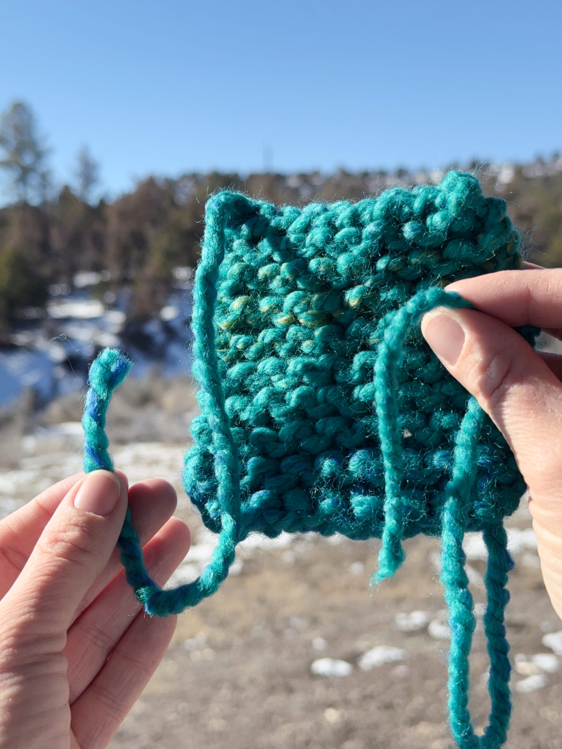 Finished beginner knit coaster showing loose ends woven into the fabric in a kids knitting lesson.
