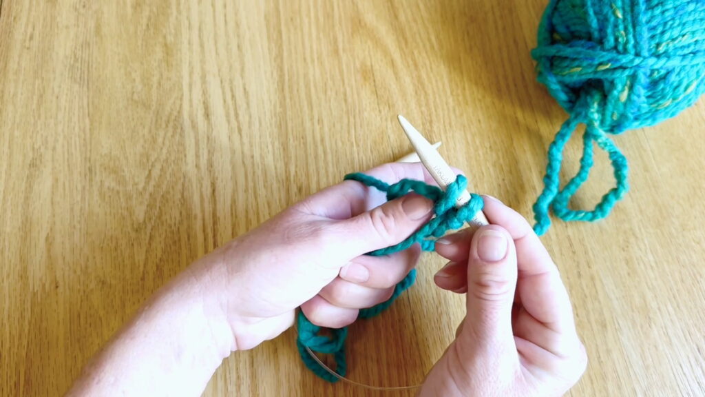 New cast on stitch slid off the thumb and placed onto the knitting needle.