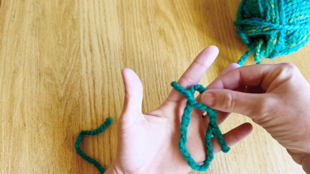 Yarn loop being pulled under the wrapped strand to form a small loop.