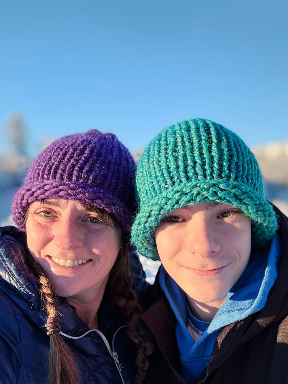 Super-bulky hats made with knit stitches on an adult and child outside in the snow.