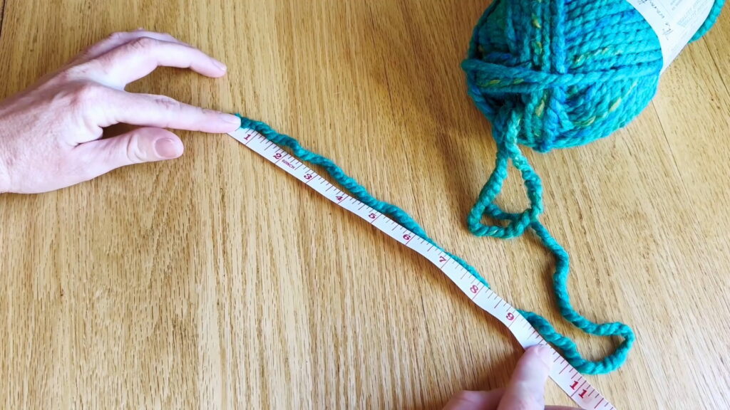 Yarn pulled from the ball to measure a long tail before making a slipknot.