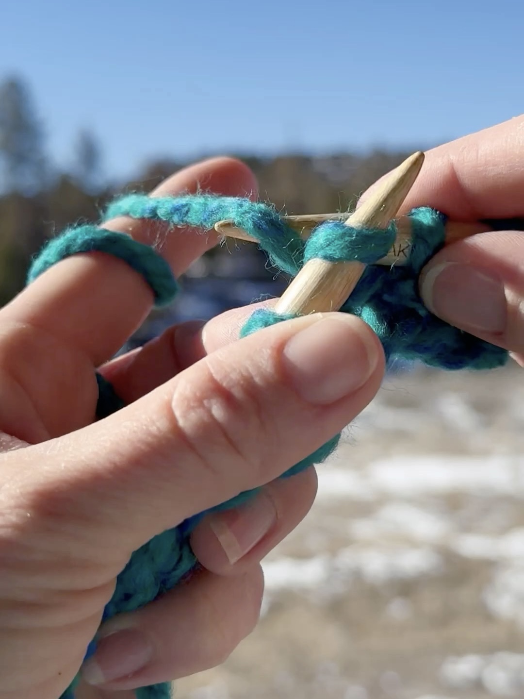 Hands holding yarn to demonstrate making the knit stitch.