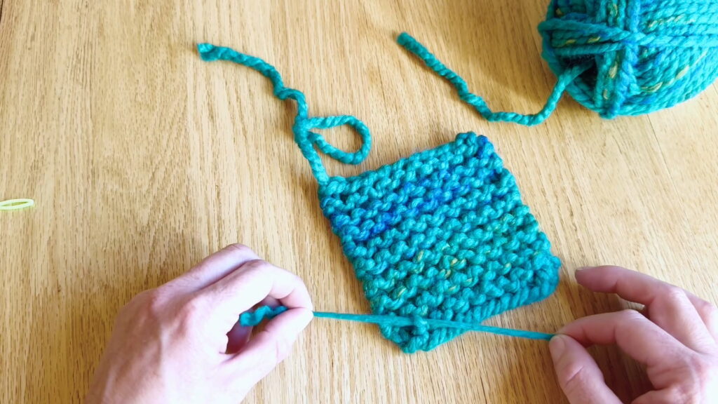 Laying the two split yarn ends in opposite directions before tying knots to secure the knitting project.