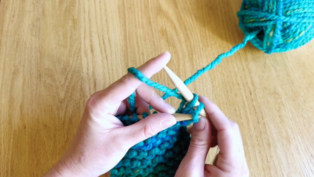 Left needle lifting the first stitch over the second stitch during the bind off process.