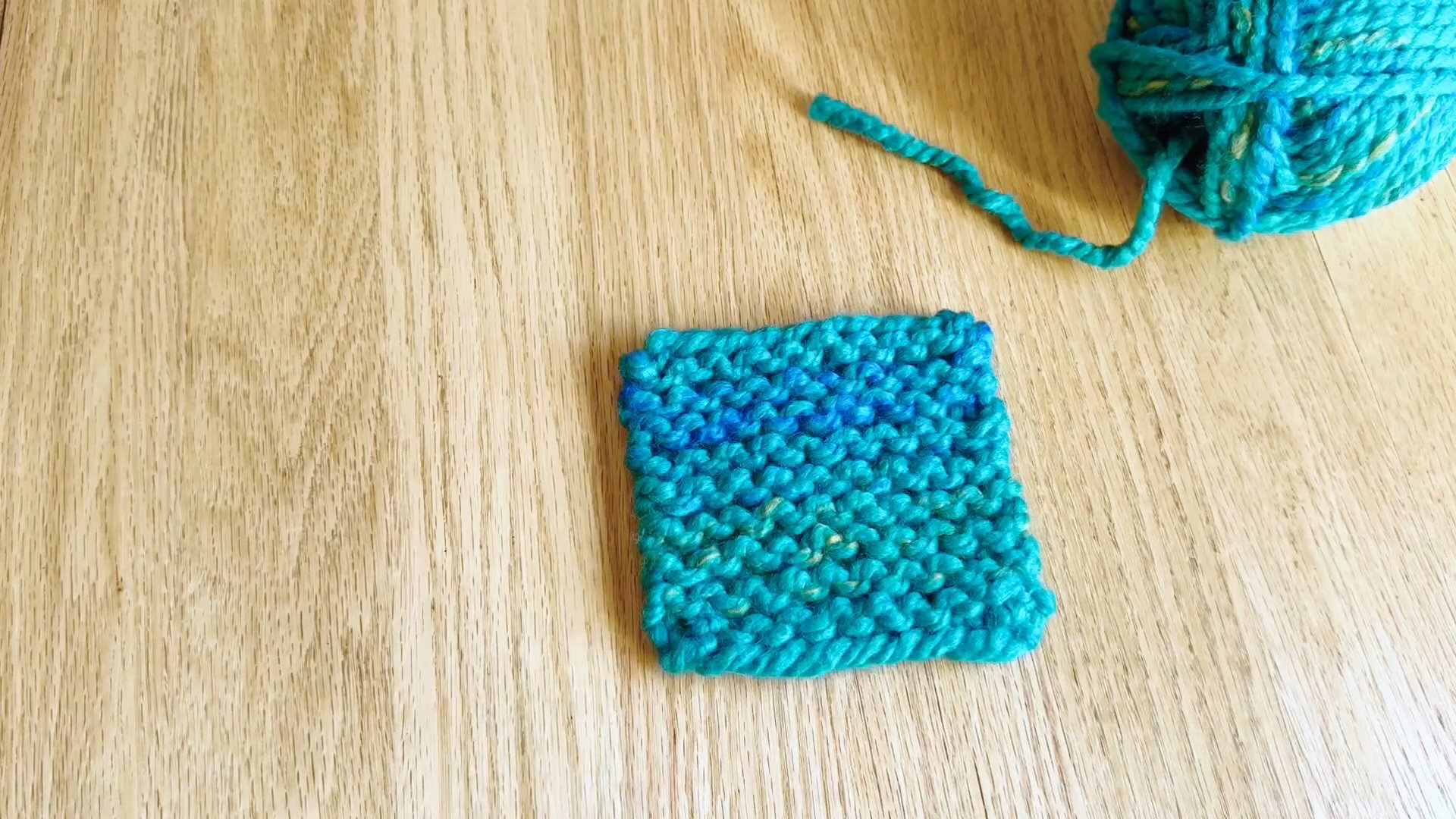 Completed beginner knit coaster with all loose ends woven in and trimmed.