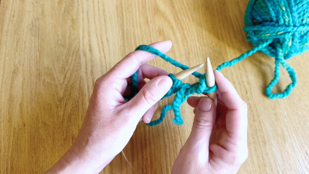 Old stitch sliding off the left needle, leaving the new knit stitch on the right needle.