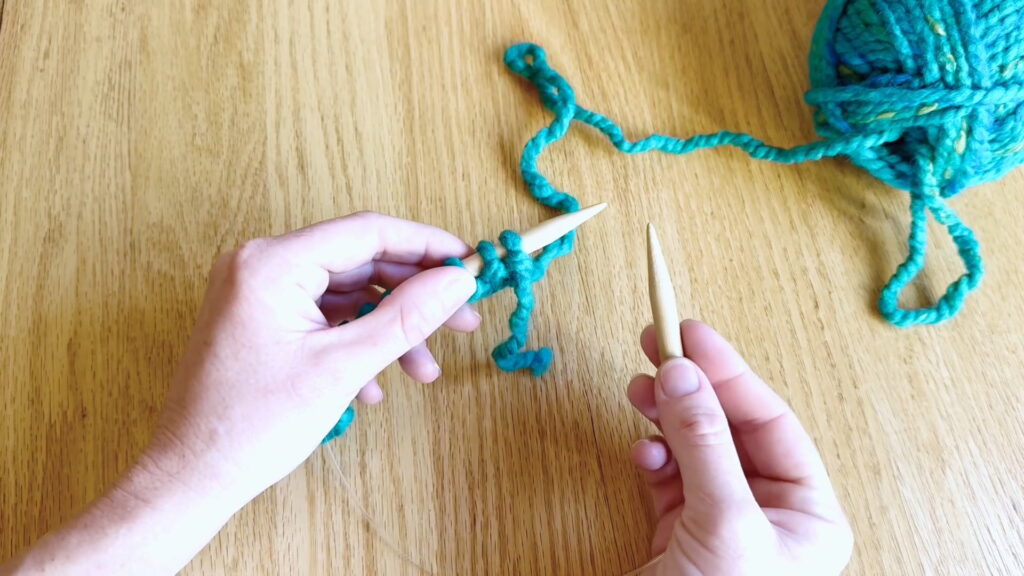 A completed row of knit stitches held in the left hand after turning the work.