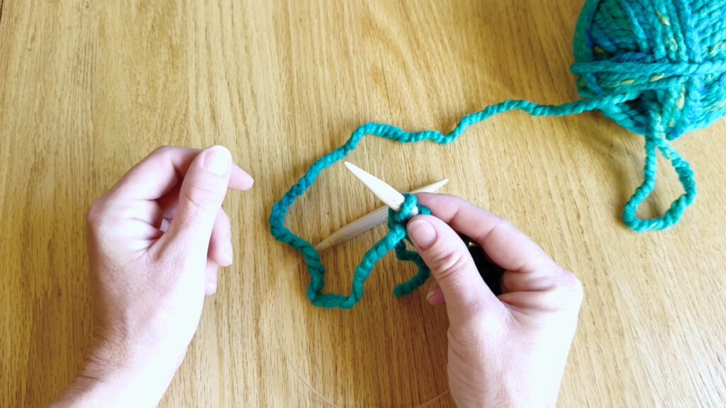 A completed row of knit stitches held in the right hand before turning the work.