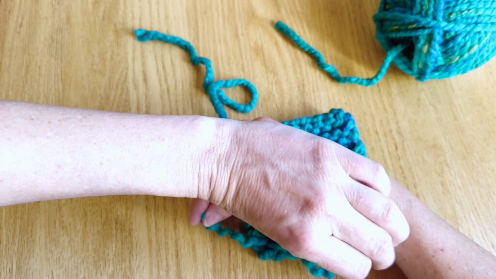 Holding the two yarn halves in opposite hands to prepare for tying a securing knot in beginner knitting.