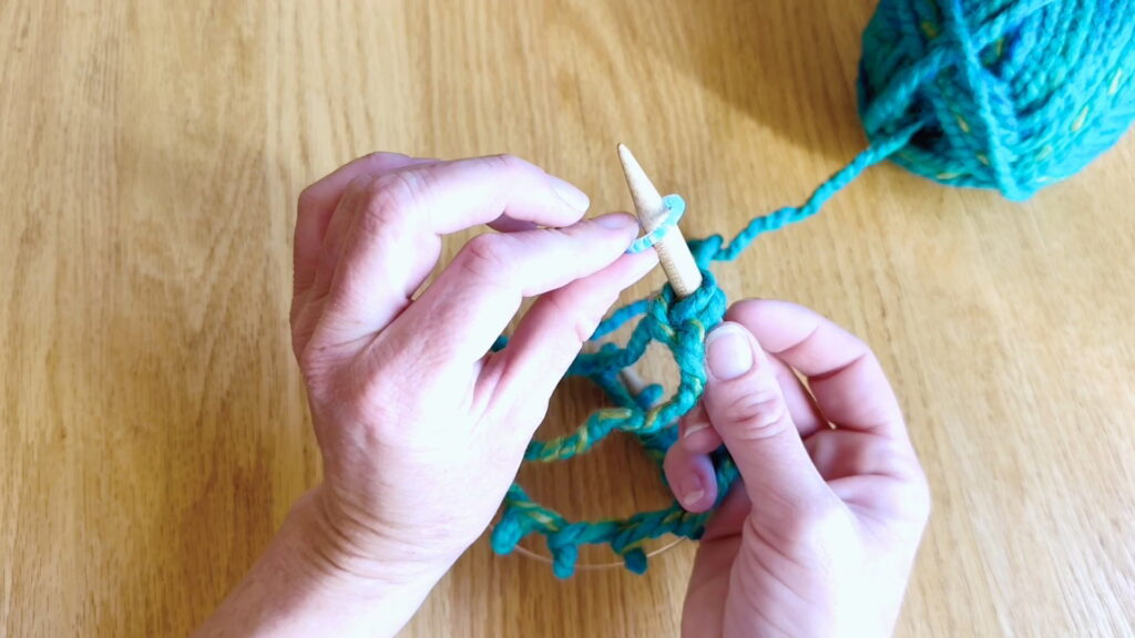 Lesson 8, Kids' Knitting Guide – placing a stitch marker after casting on to prepare for knitting in the round.