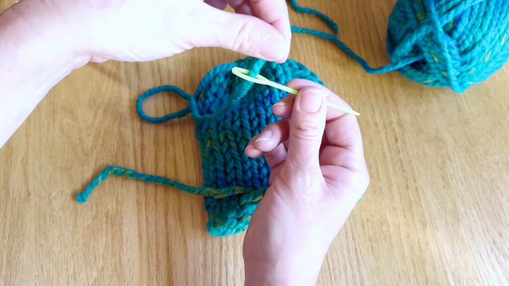 Lesson 10, Kids' Knitting Guide – threading yarn onto a darning needle to weave in loose ends on a hat.