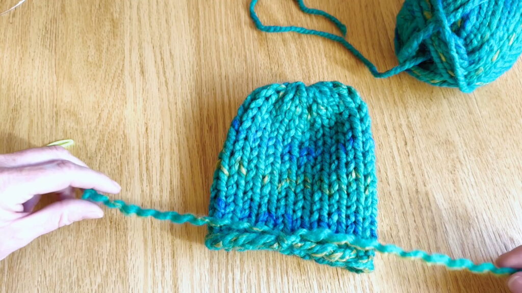 Lesson 10, Kids' Knitting Guide – laying split yarn ends in opposite directions at the bottom of a hat.
