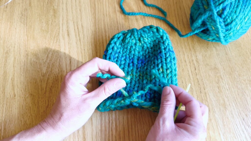 Lesson 10, Kids' Knitting Guide – splitting yarn to prepare for securing the loose end at the bottom of a hat.