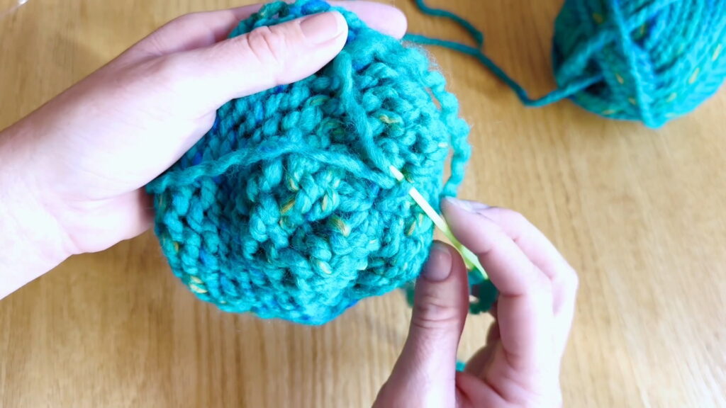 Lesson 10, Kids' Knitting Guide – splitting yarn and anchoring it to secure a loose end in a knitted hat.