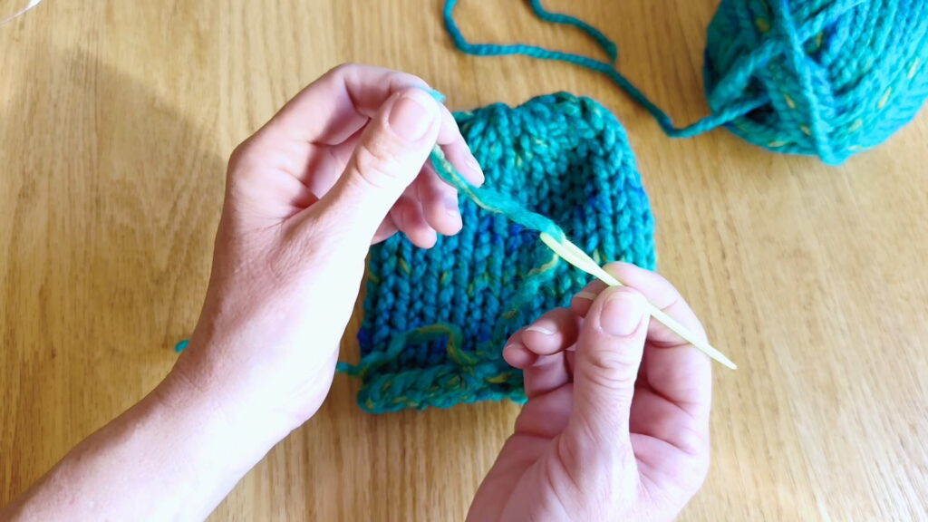 Lesson 10, Kids' Knitting Guide – threading half the yarn onto a needle to secure the loose end.