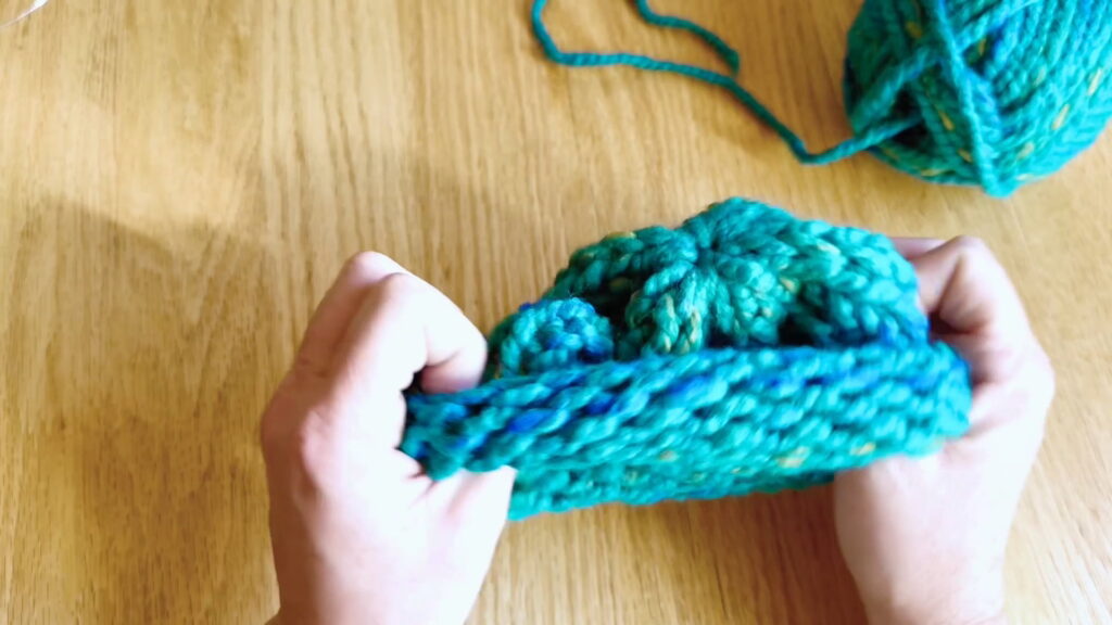 Lesson 10, Kids' Knitting Guide – turning a knitted hat right side out after finishing the top.