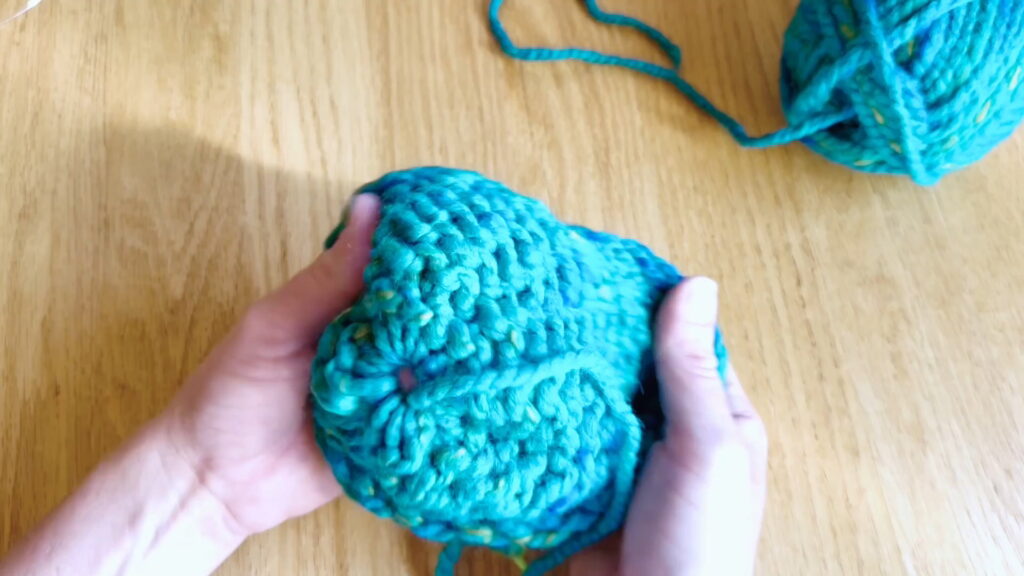 Lesson 10, Kids' Knitting Guide – turning a knitted hat inside out to pull the yarn tail through the top.